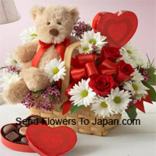 Ein schöner Korb aus roten Rosen, weißen Gerberas und saisonalen Füllstoffen, eine importierte Schachtel Schokolade und ein niedlicher brauner Teddybär