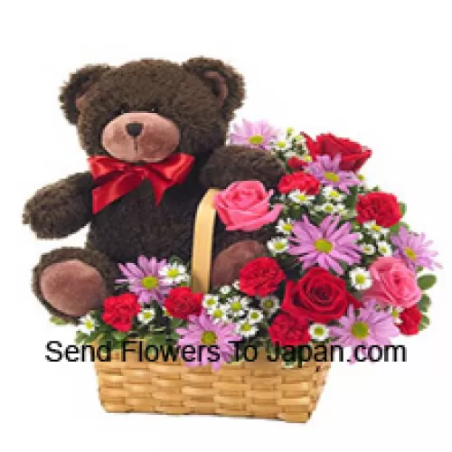 Un bellissimo cesto composto da rose rosse e rosa, garofani rossi e altri fiori viola assortiti insieme a un tenero orsacchiotto alto 14 pollici