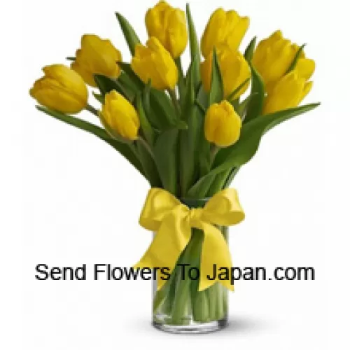 Tulipes jaunes avec des garnitures saisonnières et des feuilles dans un vase en verre - Veuillez noter que en cas de non disponibilité de certaines fleurs saisonnières, celles-ci seront remplacées par d'autres fleurs de même valeur
