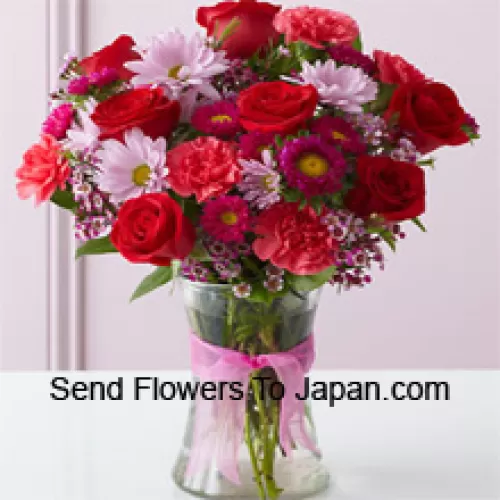 Rose rosse, garofani rossi e altri fiori assortiti disposti splendidamente in un vaso di vetro