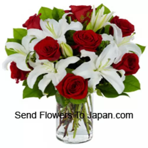Rose rosse e gigli bianchi con riempitivi stagionali in un vaso di vetro
