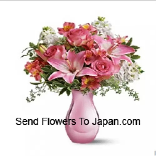 Rosas rosadas, lirios rosados y flores blancas variadas con algunos helechos en un jarrón de vidrio